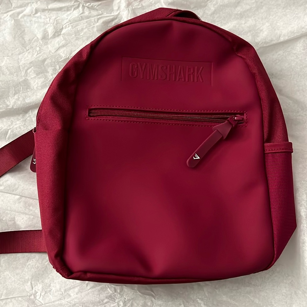 Gymshark Mini backpack
Burgundy 
Inside pocket 
2 side pockets 
1 front pocket